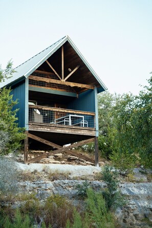 Ein zweistöckiges Holzhaus mit Balkon, umgeben von dichter Vegetation.