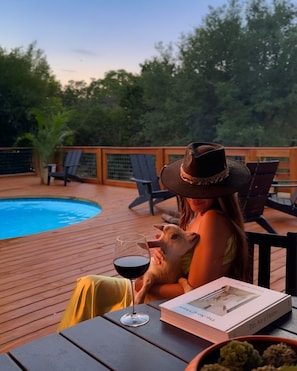 A person sitting at a wooden table with a glass of red wine, a book titled 'The Art of House', and a small dog. - Whole Ranch Buyout for your team or family! (Dripping Springs)