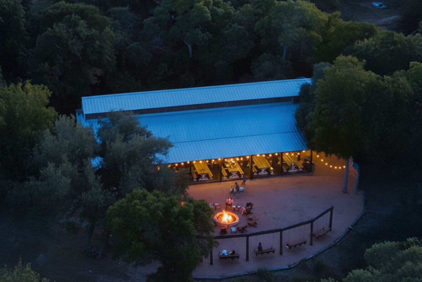 Luftaufnahme eines Gebäudes mit überdachter Terrasse, Feuerstelle und Außenmöbeln.