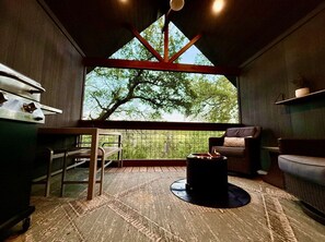 A cozy room with a large window, a fireplace, and a dining area. - Whole Ranch Buyout for your team or family! (Dripping Springs)