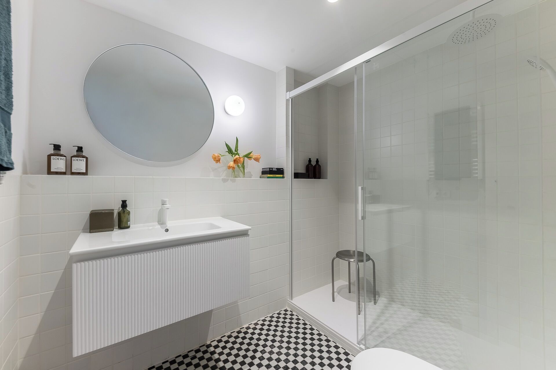 Ein modernes Badezimmer mit Waschbecken, Spiegel und einer Duschkabine aus Glas.