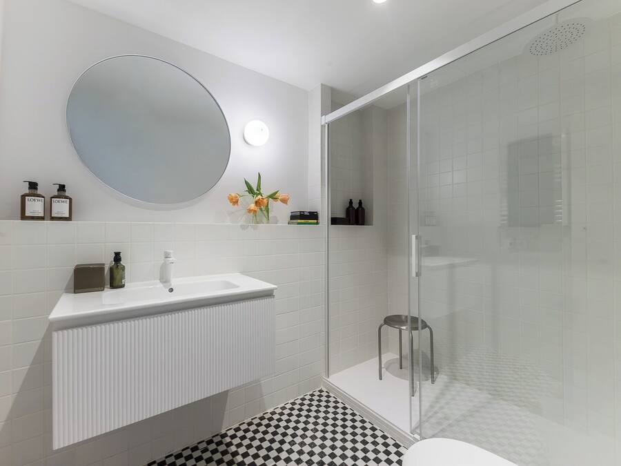 Ein modernes Badezimmer mit Waschbecken, Spiegel und einer Duschkabine aus Glas.