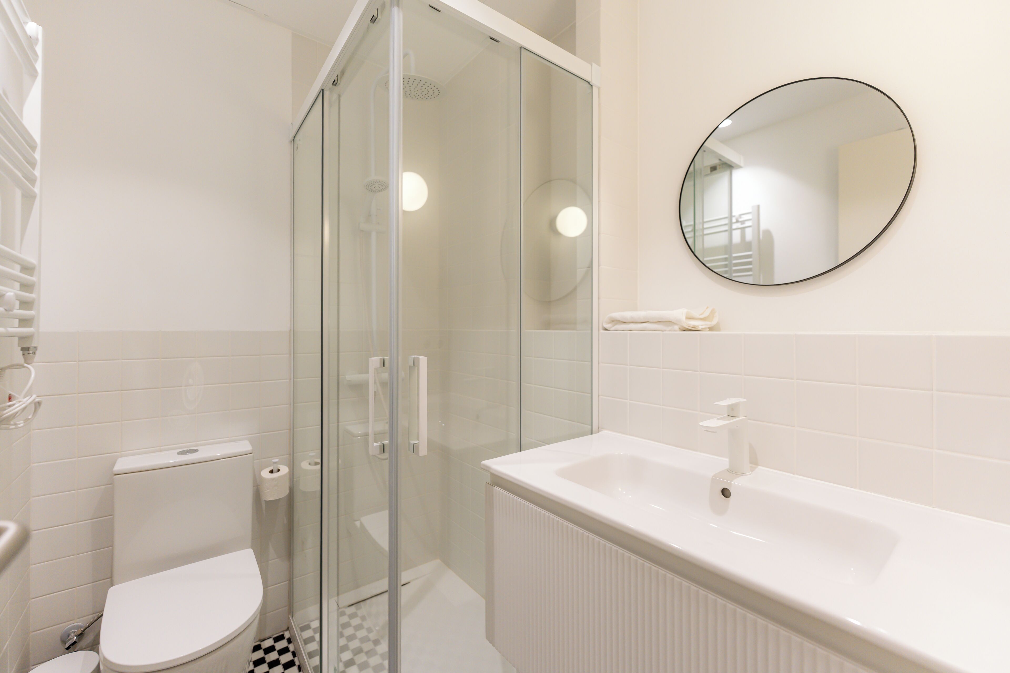 A bathroom with a toilet, a glass-enclosed shower, a sink, and a mirror.