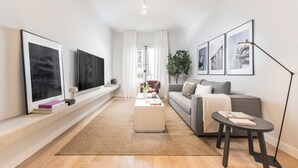 A modern living room with a sofa, coffee table, and TV. - Edmond Vibes Plaza de España Suites (Madrid)