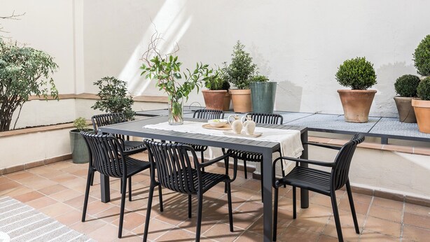 A patio with a table and chairs, surrounded by potted plants. - Edmond Vibes Plaza de España Suites (Madrid)
