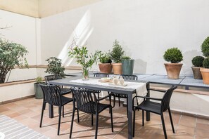 Un patio con una mesa y sillas, rodeado de plantas en macetas.