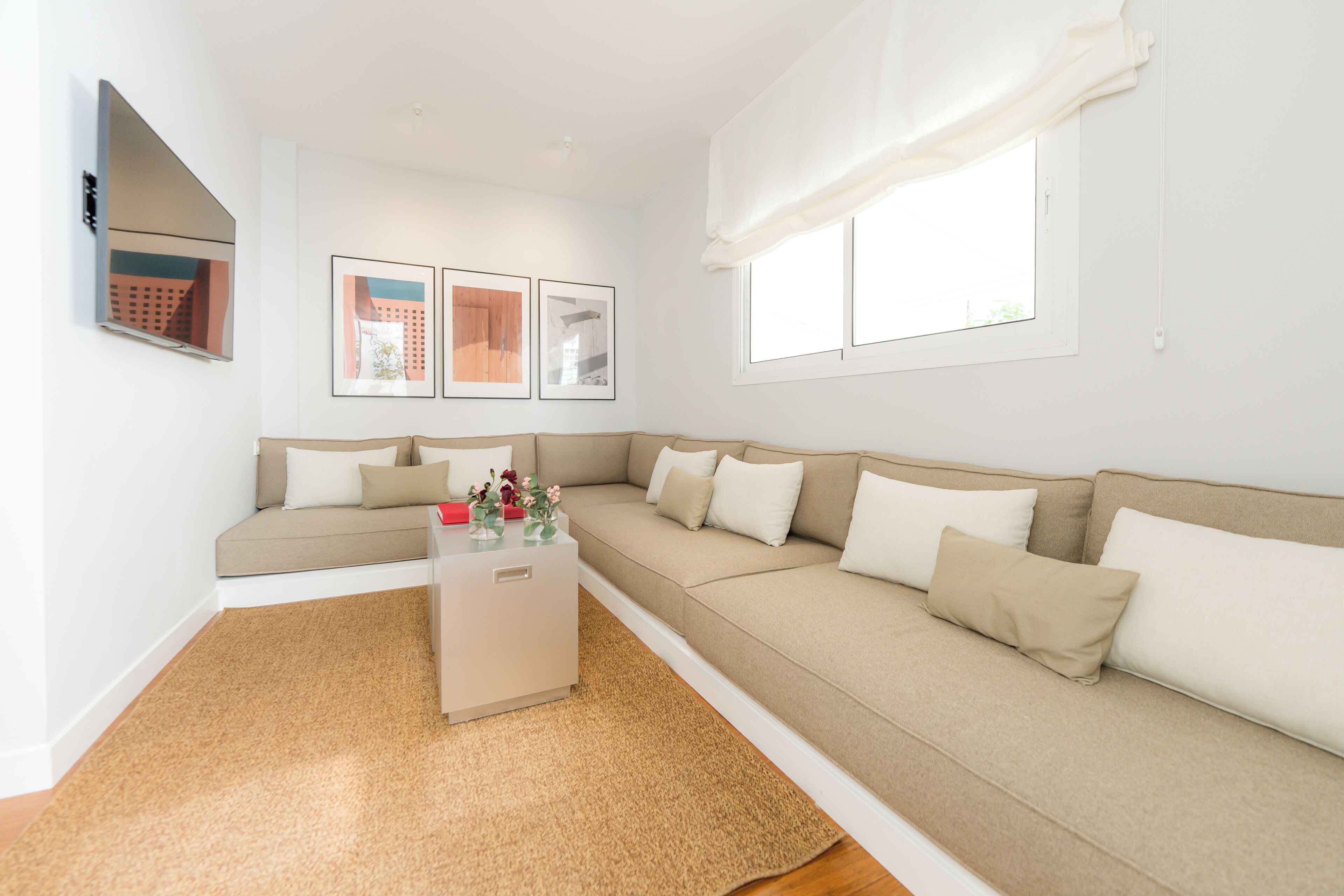 Ein Wohnzimmer mit einem beigefarbenen Sofa, einem Couchtisch und gerahmten Bildern an der Wand.