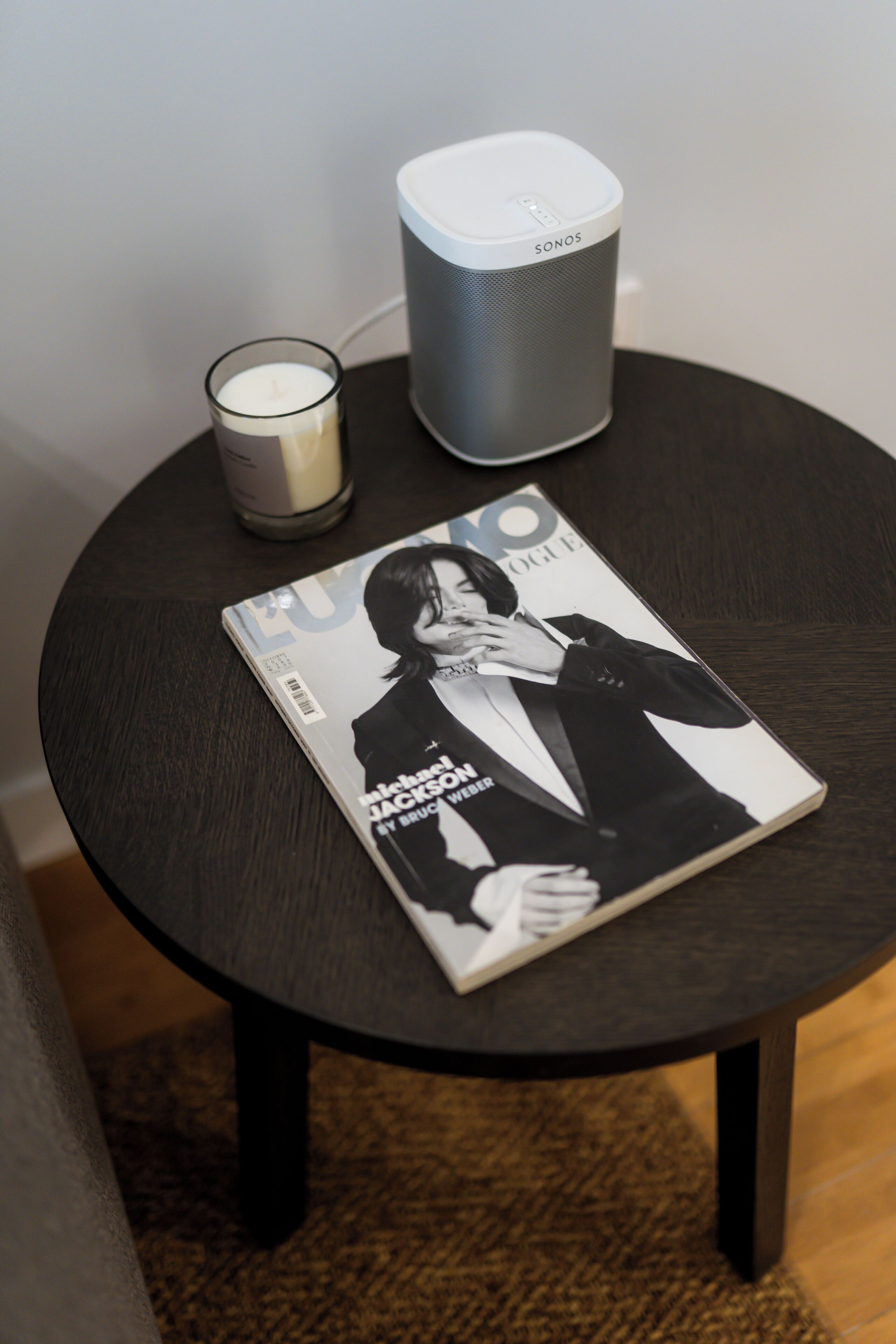 A magazine on a table with a speaker and a candle.