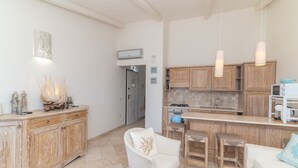 Eine moderne Küche mit Holzausbau, einer zentralen Kücheninsel, Barhocker und einem weißen Sofa.