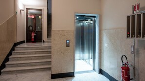 A modern elevator with a digital display, a fire extinguisher, and a fire alarm sign. - U Genova (Genoa)