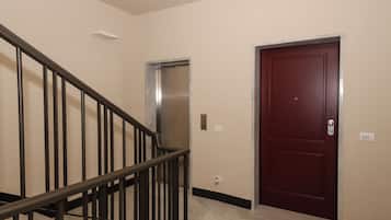 Una scala con ringhiera in metallo che porta a un ascensore e a una porta con una targa identificativa.