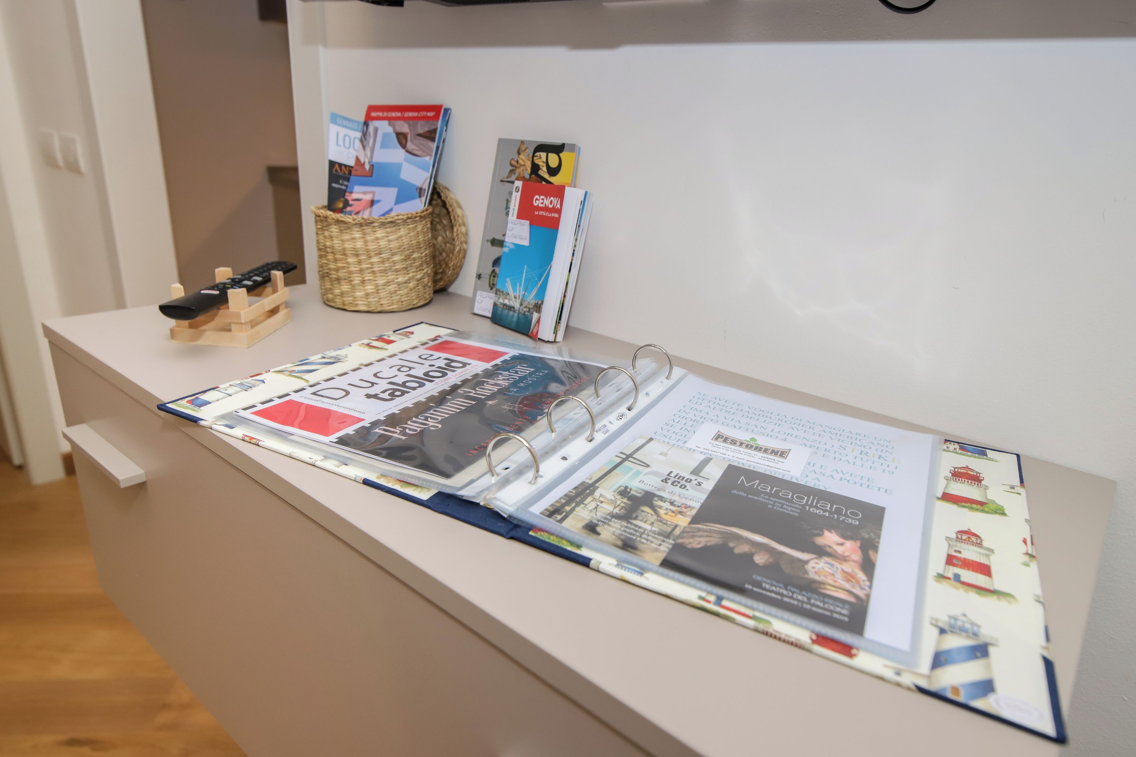 Et magasin med forskellige publikationer, en fjernbetjening og en kurv af fletværk.