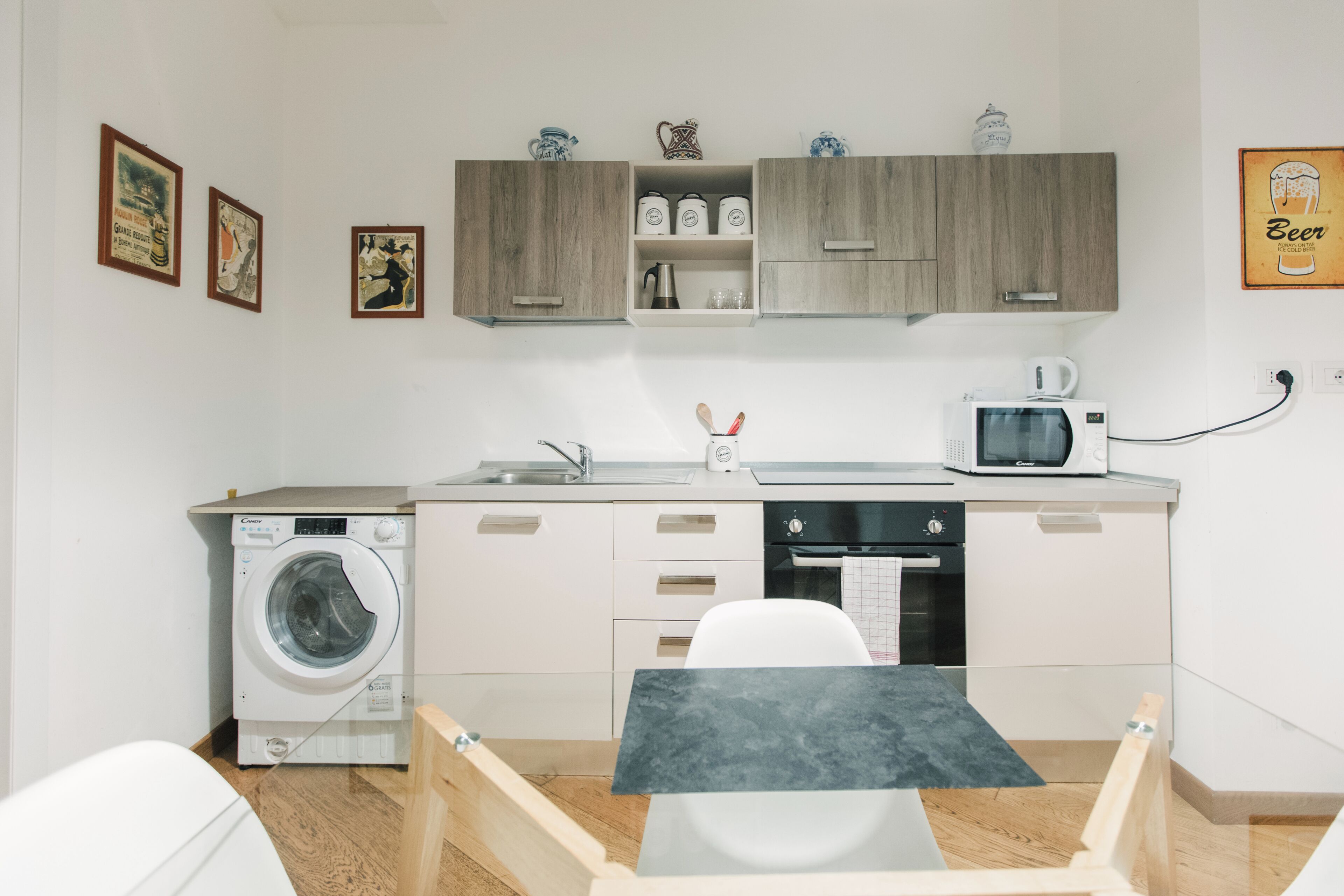 A compact kitchen with a washing machine, microwave, and a small dining area.
