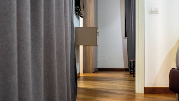 A hallway with wooden flooring, a lamp, and a door leading to another room. - U Genova (Genoa)