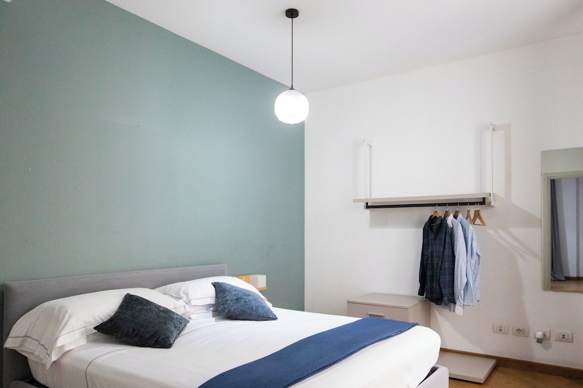 Un dormitorio moderno con una cama, una mesita de noche y un perchero.