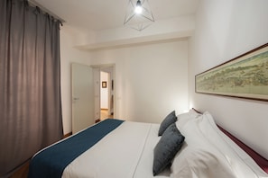 Un dormitorio con una cama, un cuadro en la pared y una puerta que da a otra habitación.