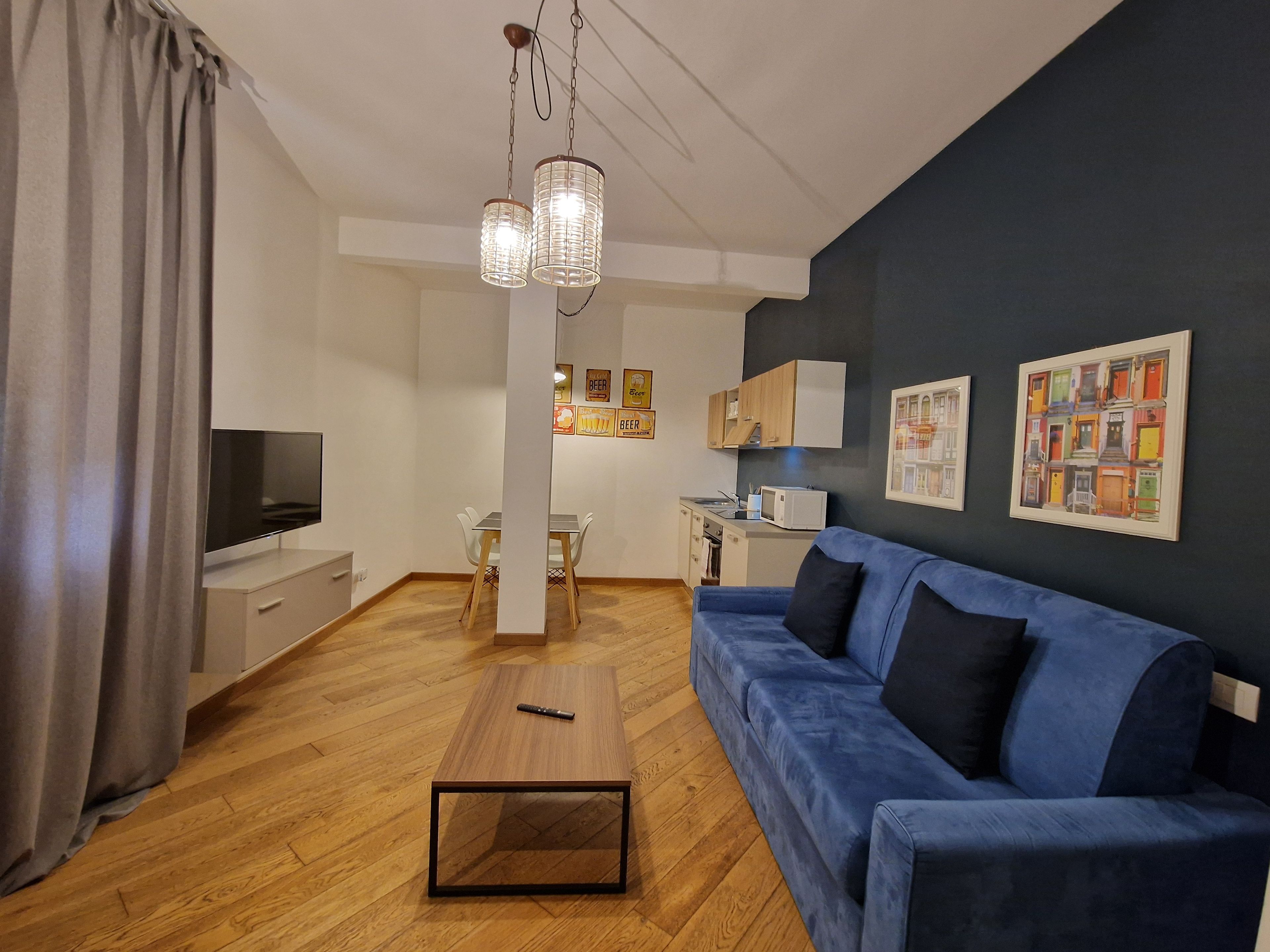 Una sala moderna con un sofá azul, una mesa de centro de madera y un televisor.