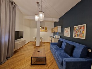 A modern living room with a blue sofa, wooden coffee table, and a TV.