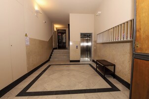 A hallway with a tiled floor, a bench, and an elevator.