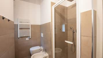 Deluxe appartement | Badkamer | Een douche, een haardroger, handdoeken, zeep