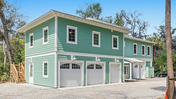 A two-story house with a green exterior, white trim, and multiple garage doors.