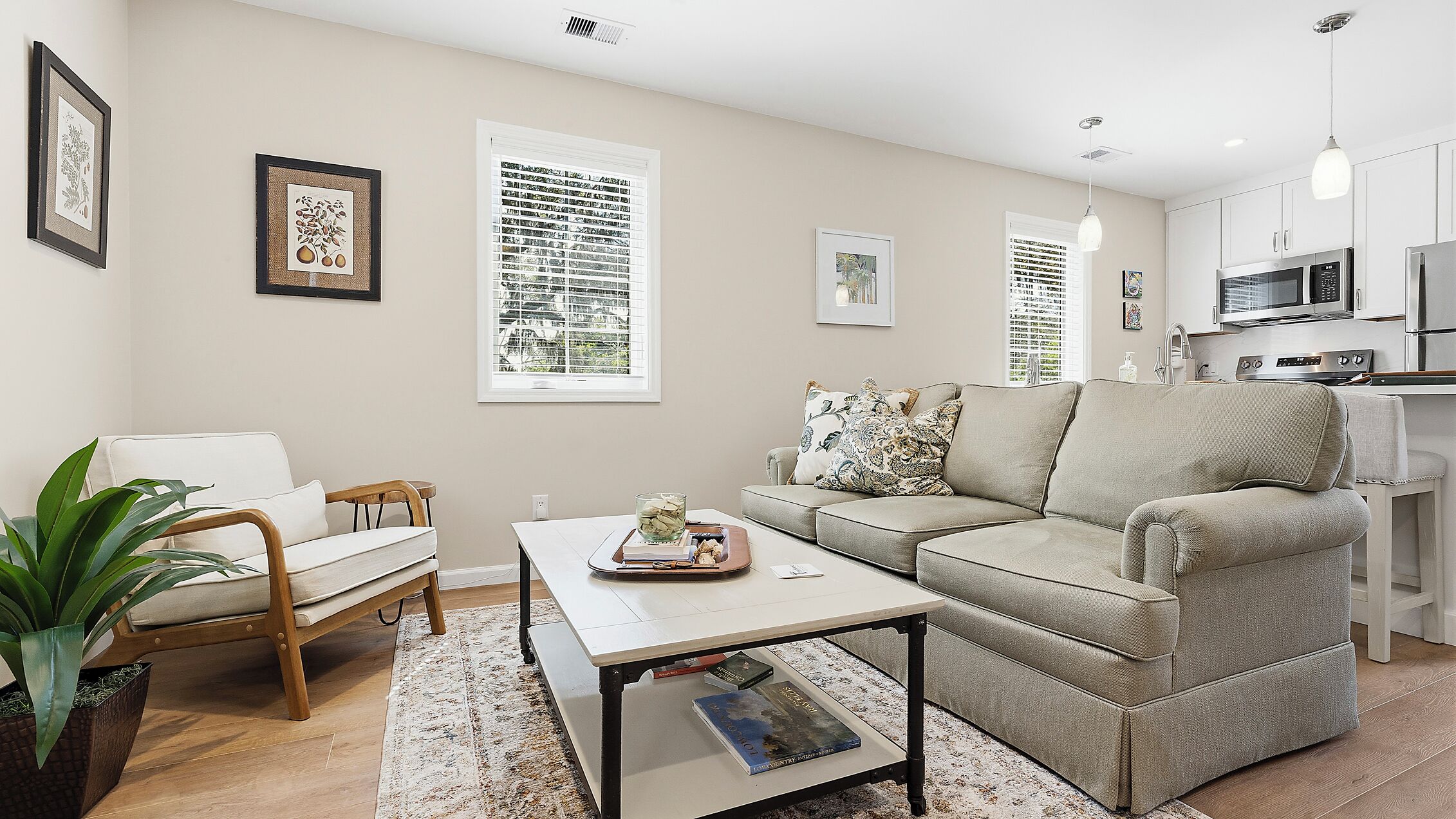 A modern living room with a sofa, coffee table, and a dining area with a kitchen in the background.