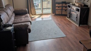 A living room with a brown leather sofa, a flat-screen TV, a wooden cabinet, and a view of a snowy landscape through a sliding glass door. - 4301  Hot tub, sauna & more resort amenities  Shepherd's Retreat (Beech Mountain)