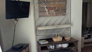 A living room with a TV mounted on the wall, a wooden cabinet with baskets, a fireplace, and a herringbone-patterned wall. - 4301  Hot tub, sauna & more resort amenities  Shepherd's Retreat (Beech Mountain)