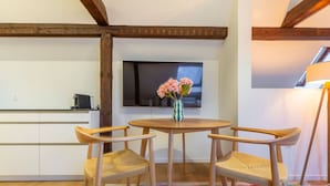 A dining area with a round wooden table, three wooden chairs, and a vase with flowers. - Cosy 1-BR for two · central Zürich · self check-in (Zürich)