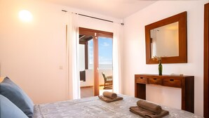 A bedroom with a bed, a dresser, a mirror, a window, and a door leading to a balcony. - Vacation Villa 'Rubicon' with Sea View, Wi-Fi and Air Conditioning (Yaiza)