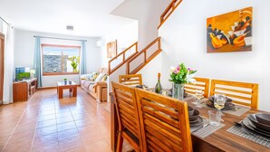 A modern living room with a dining area, wooden furniture, a staircase, and a painting on the wall. - Vacation Villa 'Rubicon' with Sea View, Wi-Fi and Air Conditioning (Yaiza)