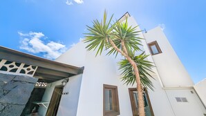 A modern building with a white facade, a palm tree, and a clear blue sky. - Vacation Villa 'Rubicon' with Sea View, Wi-Fi and Air Conditioning (Yaiza)