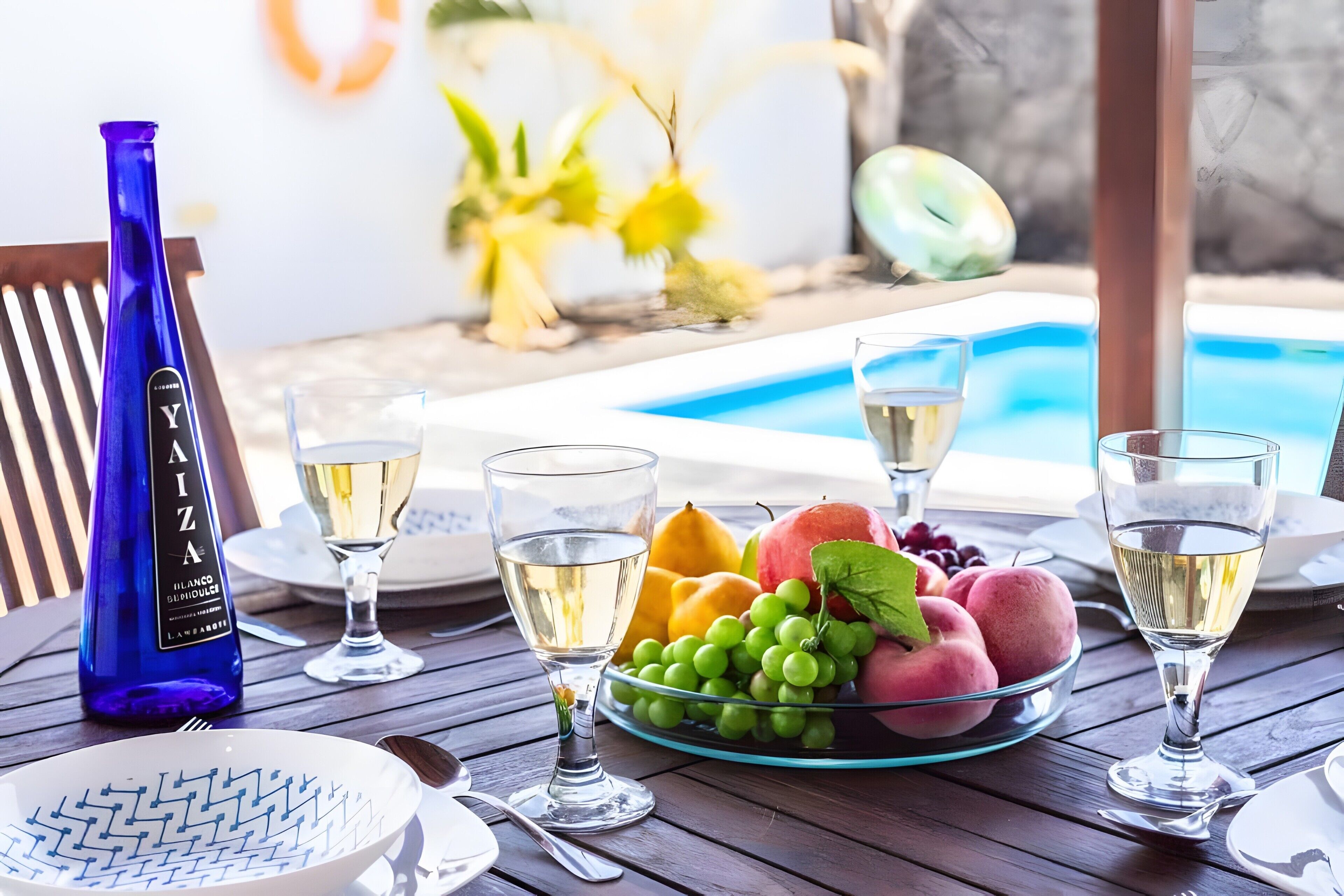 Ein Esstisch mit einer Flasche, Gläsern, Früchten und einer Schüssel.