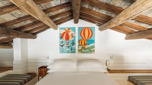 A bedroom with a large bed, two nightstands, and a wooden ceiling. There are two paintings on the wall. - Casa Adriana, a Burghesius home (Roma)