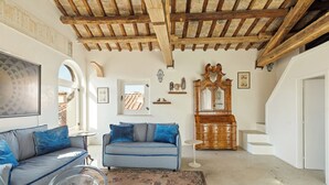 A living room with a blue sofa, a wooden cabinet, and a large mirror. - Casa Adriana, a Burghesius home (Roma)