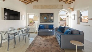 A modern living room with a glass dining table, a grey sofa, and a patterned rug. - Casa Adriana, a Burghesius home (Roma)