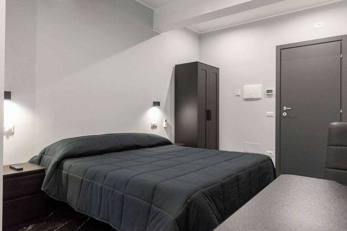 Une chambre d’hôtel moderne équipée d’un lit, d’une armoire, d’un bureau et d’une chaise.