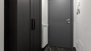 Un pasillo con una puerta oscura, un radiador y suelo de mármol.