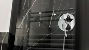Un baño con un grifo moderno y pared de mármol.