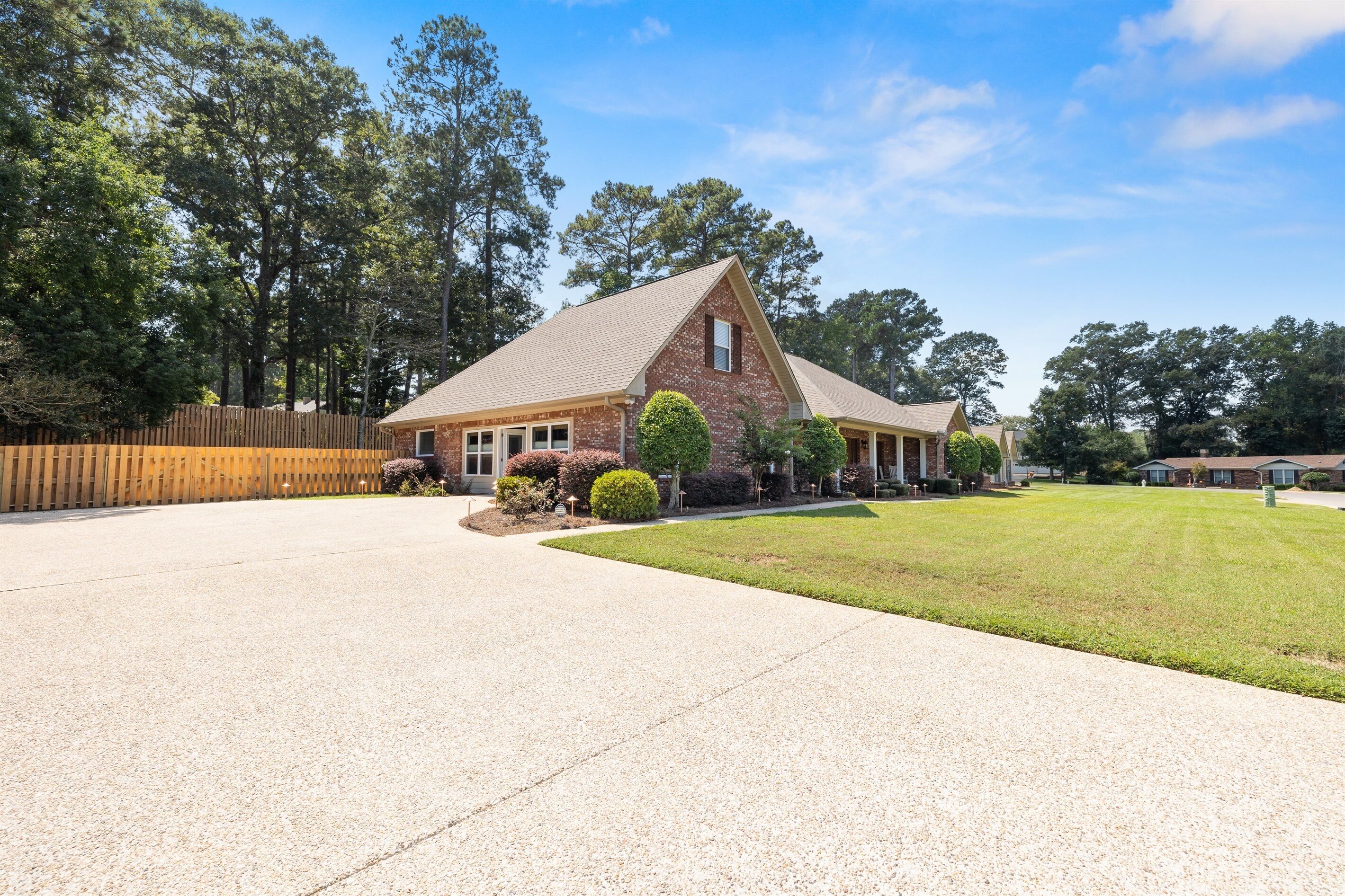 A single-story brick house with a sloped roof, a covered porch, and a well-maintained lawn.
