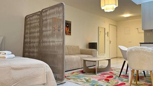 Et moderne soveværelse med seng, sofa, spisebord og en dekorativ rumdeler.