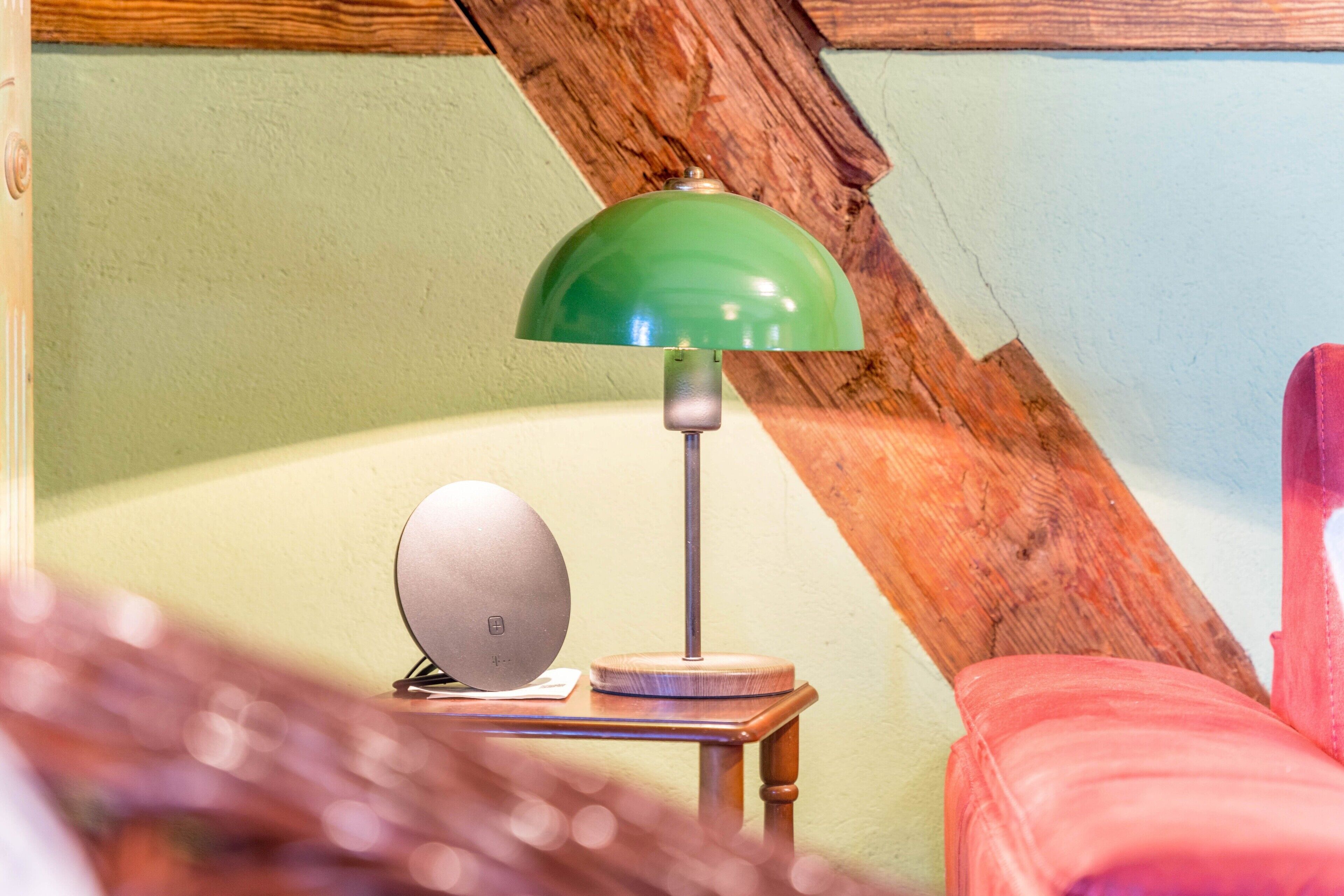 Une pièce avec une lampe verte, une petite table et une chaise rouge.