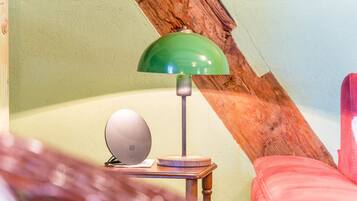 Une pièce avec une lampe verte, une petite table et une chaise rouge.