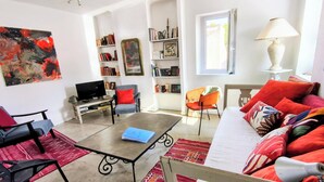 A living room with a sofa, chairs, a coffee table, a TV, bookshelves, and a painting. - New! Charm, ideal location, 2 bedrooms, air conditioning, balcony with view. (Sète)