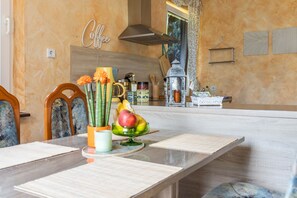 Eine Küche mit Marmorarbeitsplatte, einem Schild mit der Aufschrift ‚Kaffee‘ an der Wand und einem Essbereich mit Tisch für zwei Personen.