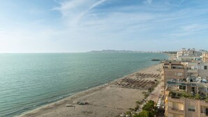 Paesaggio costiero con spiaggia, edifici e cielo sereno.