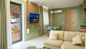 Un soggiorno moderno con divano, televisore e zona pranzo.