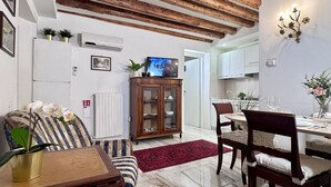 Ein Essbereich mit Holztisch, Stühlen, einem roten Teppich und einem Fernseher an der Wand.