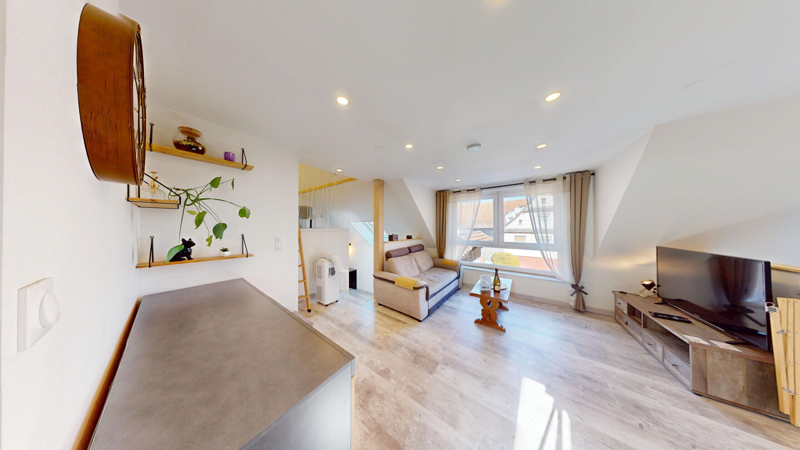 A modern living room with a sofa, TV, and a dining area.