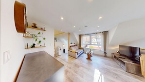 Ein modernes Wohnzimmer mit Sofa, Fernseher und Essbereich.
